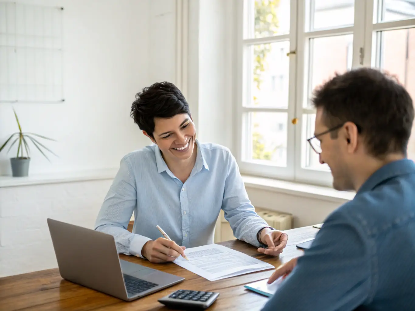 A person sitting at a desk, reviewing financial documents with a consultant, both smiling and engaged in a discussion about investment strategies.